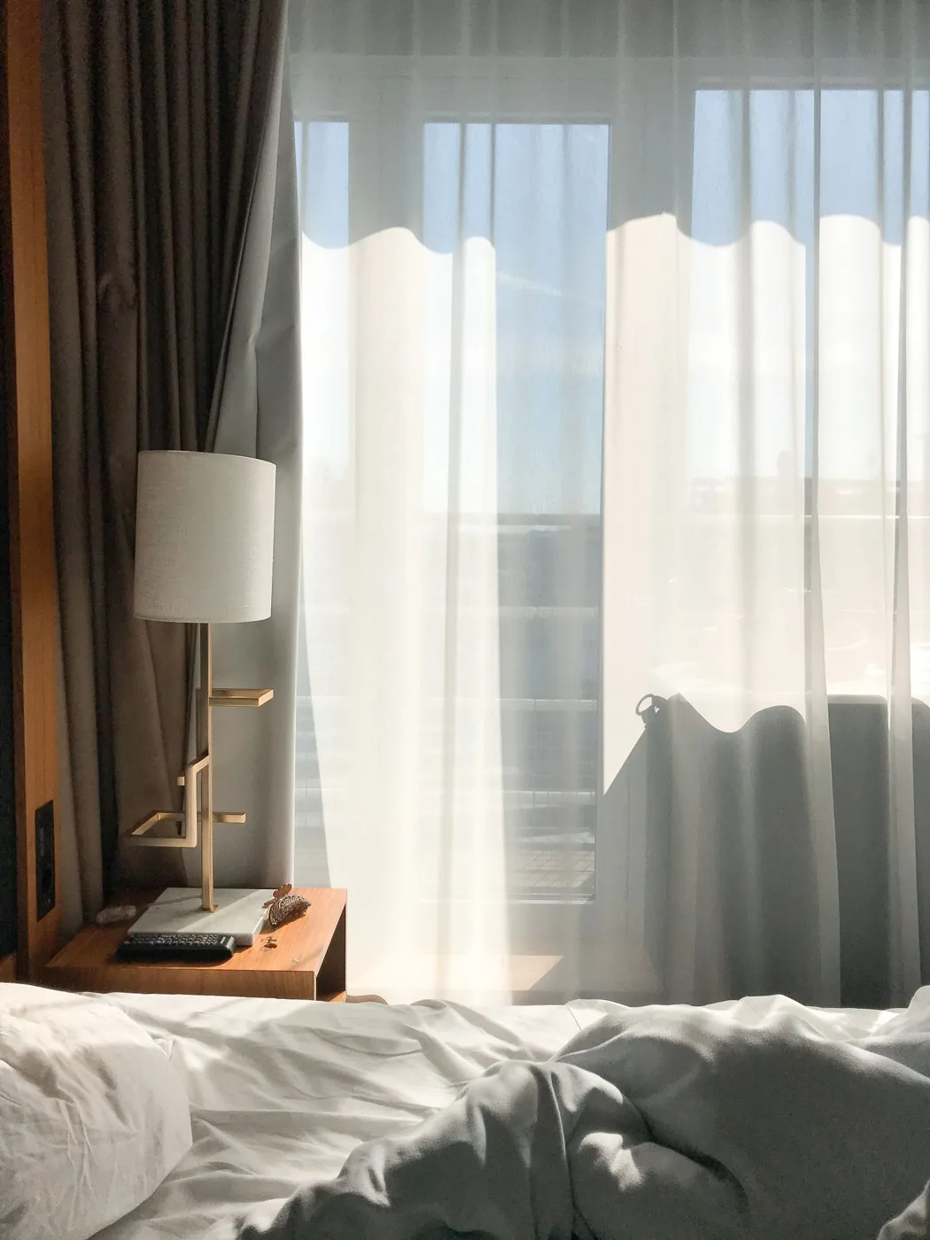 Interior of bedroom with curtain illuminated by sunlight